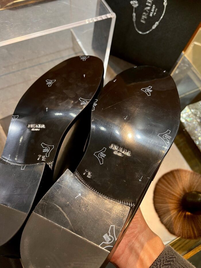 Scarpe di lusso con suola elegante e logo distintivo, presentate in teca raffinata.