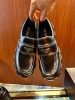 Scarpe loafer di lusso in pelle nera con logo elegante e suola robusta.