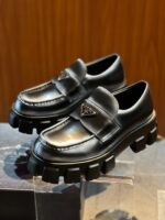 Sneakers Prada di lusso con suola chunky in pelle nera e dettagli logo elegante.