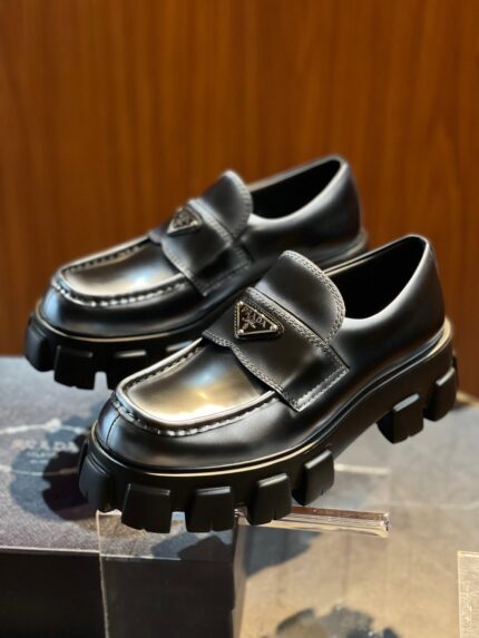 Scarpe slip-on in pelle lucida con suola chunky e logo, stile moderno e di lusso.