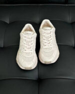 Sneakers bianche ideali per sport e casual, su fondo in pelle nero lucido.
