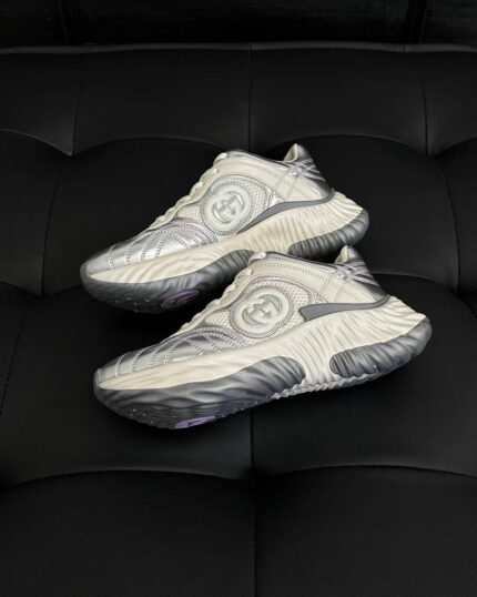 Sneakers futuristiche con logo collaborativo, design elegante, su superficie nera per un look moderno.