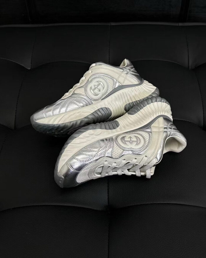 Sneakers moderne in argento e nero su superficie nera, stile raffinato e design sofisticato.