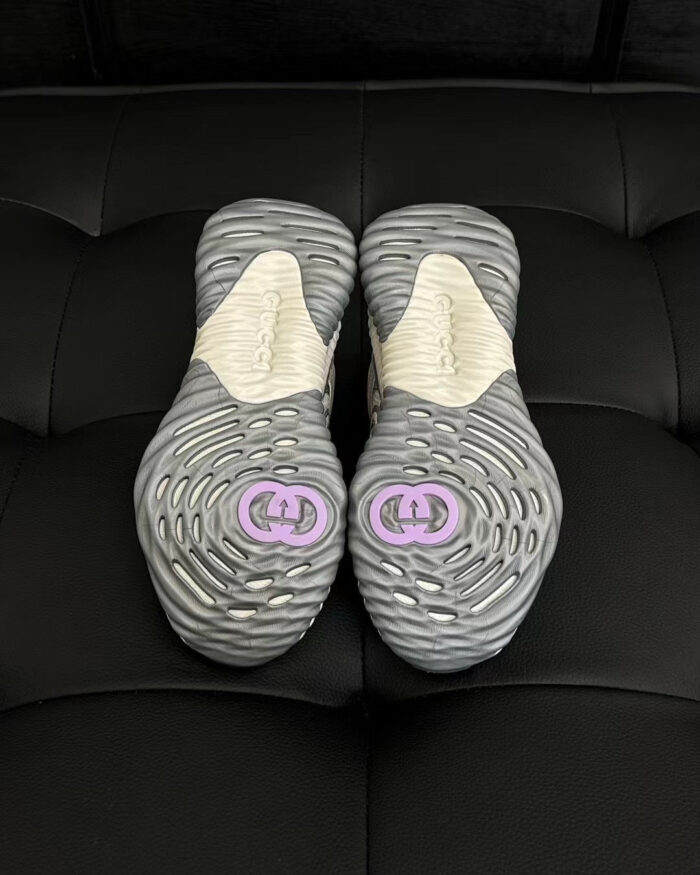 Sneakers moderne grigie con logo viola, dettagli di design e suola antiscivolo elegante.