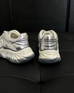 Sneakers bianche moderne con dettagli silver, suola chunky e design dinamico e futuristico.