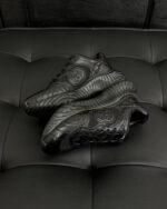Sneakers nere moderne con logo circolare e design elegante su sfondo in velluto.