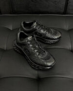 Sneaker nere moderne con suola wavy, dettagli in mesh e stile urbano versatile.