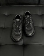 Scarpe sportive nere moderne e eleganti su sfondo nero con dettagli lucidi e design raffinato.