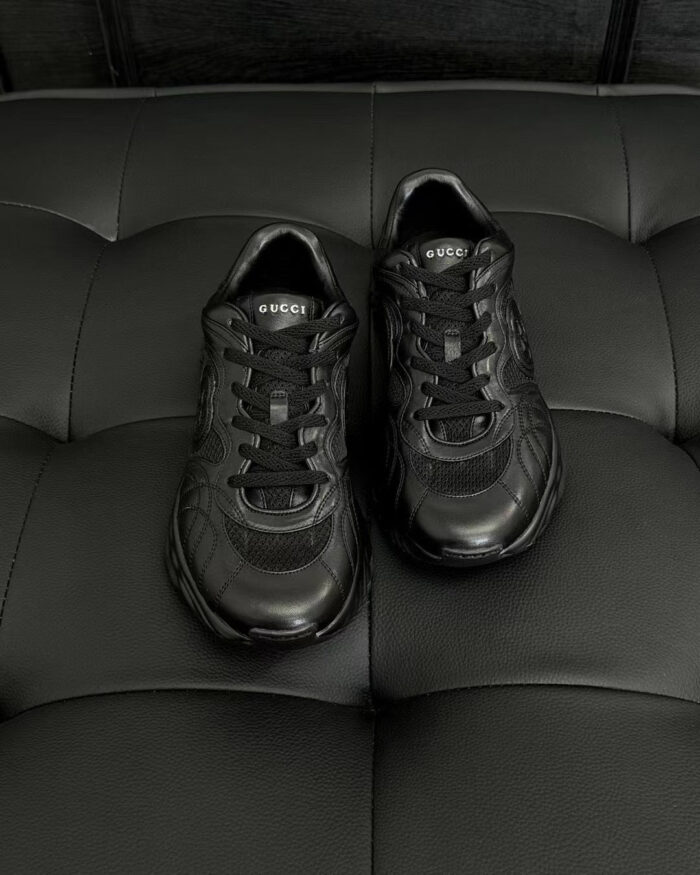 Scarpe sportive nere moderne e eleganti su sfondo nero con dettagli lucidi e design raffinato.