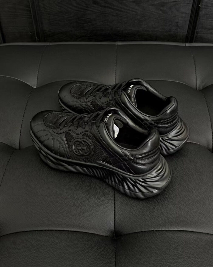 Sneakers nere in pelle lucida su divano rivestito in stile tufting elegante.