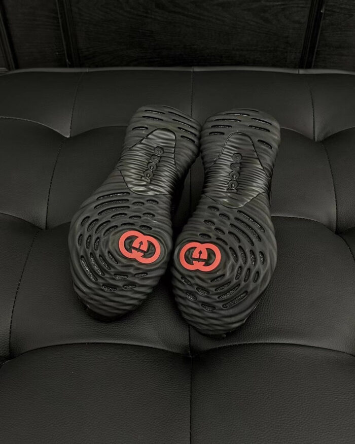 Scarpe di lusso con suole dettagliate e logo rosso su sfondo in pelle nera elegante.