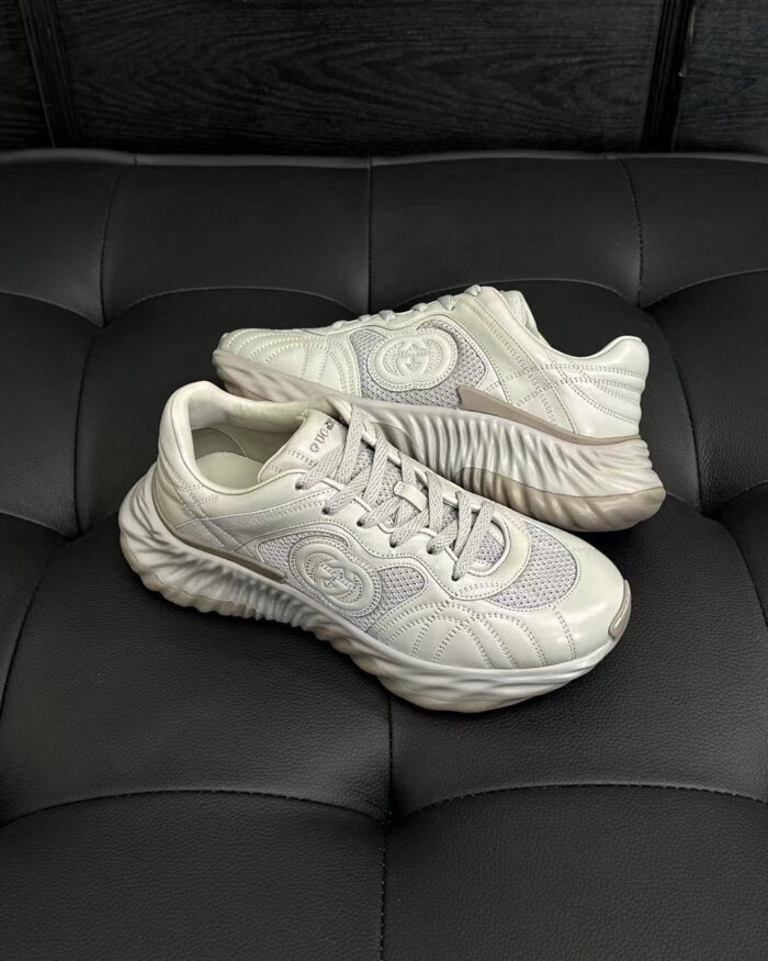 Sneakers bianche moderne con suola ondulata, dettagli in mesh e logo circolare elegante.