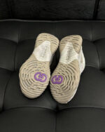 Scarpe da corsa con suola beige e logo viola, design elegante e funzionale.