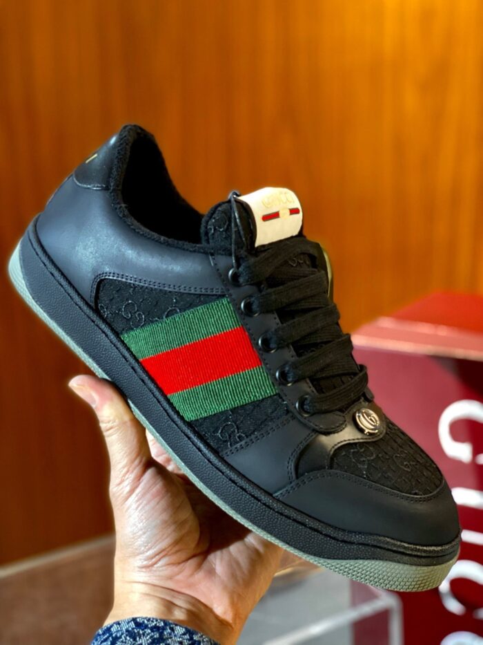 Sneaker nera elegante con dettagli verde e rosso, stile di lusso e design moderno.