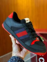 Sneaker nera con dettagli rossi e strisce blu, stile moderno e design di alta qualità.