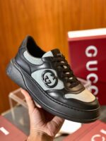 Sneaker Gucci in pelle e camoscio nero e grigio con suola chunky e logo iconico.