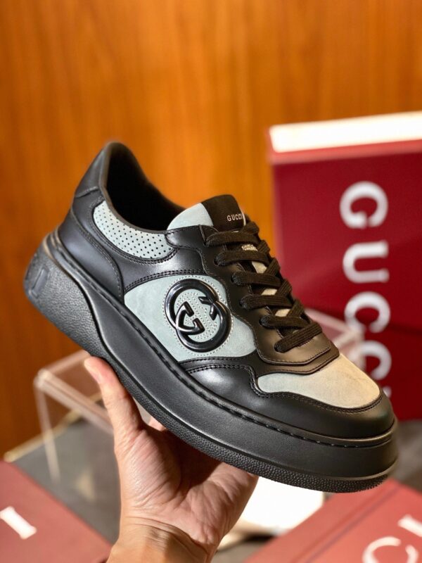 Sneaker Gucci in pelle e camoscio nero e grigio con suola chunky e logo iconico.