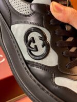 Sneaker di lusso in nero e grigio con logo grande, design minimalista e netto stile moderno.