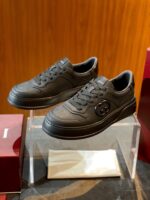 Sneakers nere di design elegante con logo, standalone su supporto in ambiente raffinato.
