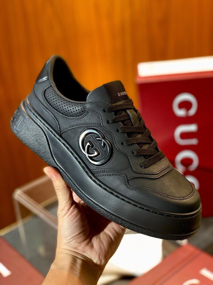 Sneaker luxury Gucci in pelle nera con logo embossato e suola leggermente rialzata.