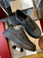 Sneakers nere di lusso con emblema elegante su superficie riflettente, stile moderno e sofisticato.