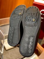 Sneakers di lusso nere con suola dettagliata e logo elegante in ambiente raffinato.