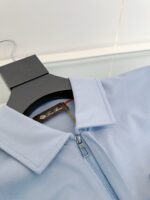 Maglietta polo azzurra con zip, stile moderno e elegante, su supporto nero in mostra.