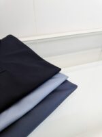 Set di vestiti eleganti colorati, ordinati su superficie in vetro con riflessi minimalisti.