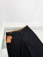 Pantaloni neri eleganti con etichetta arancione, stile moderno e alta qualità, perfetti per ogni occasione.