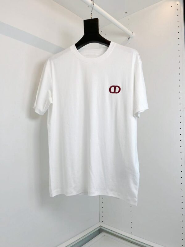Maglietta bianca minimalista con logo rosso, stile versatile e fashion, su appendiabiti nero.
