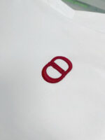 T-shirt bianca con logo ricamato rosso, stile moderno e minimalista.