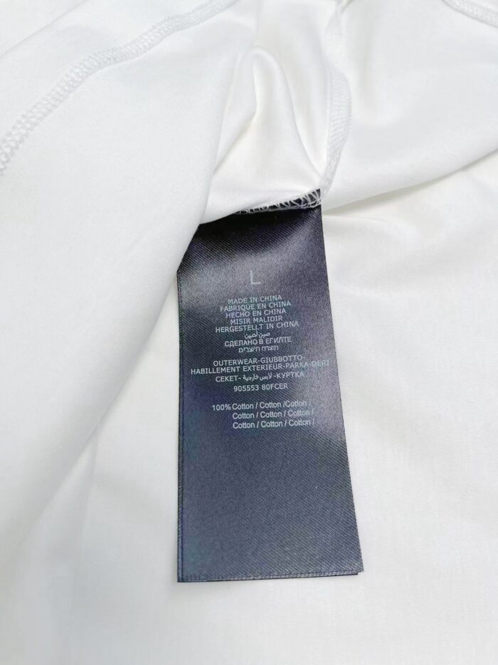 Etichetta tra cura, tag e dettaglio tessuto di un indumento in cotone bianco.