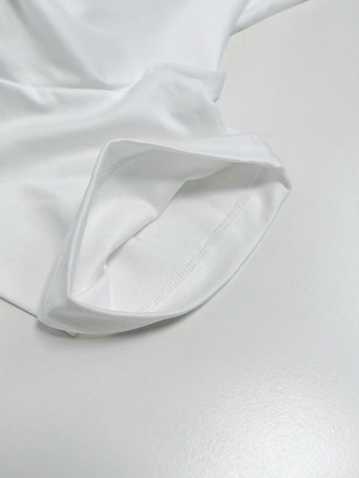 Manica elegante in cotone bianco, dettagli rifiniti, stile minimalista e versatile.