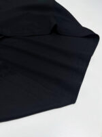 Particolare di camicia elegante in tessuto blu scuro con cuciture precise e drappeggio raffinato.