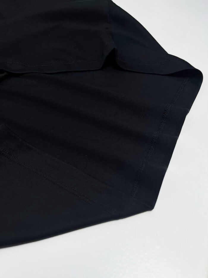 Particolare di camicia elegante in tessuto blu scuro con cuciture precise e drappeggio raffinato.