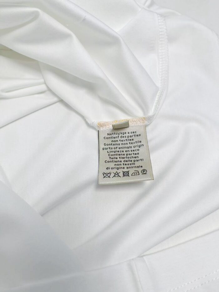 Maglietta bianca leggera con etichetta di cura, disponibile per stile casual e sportivo.
