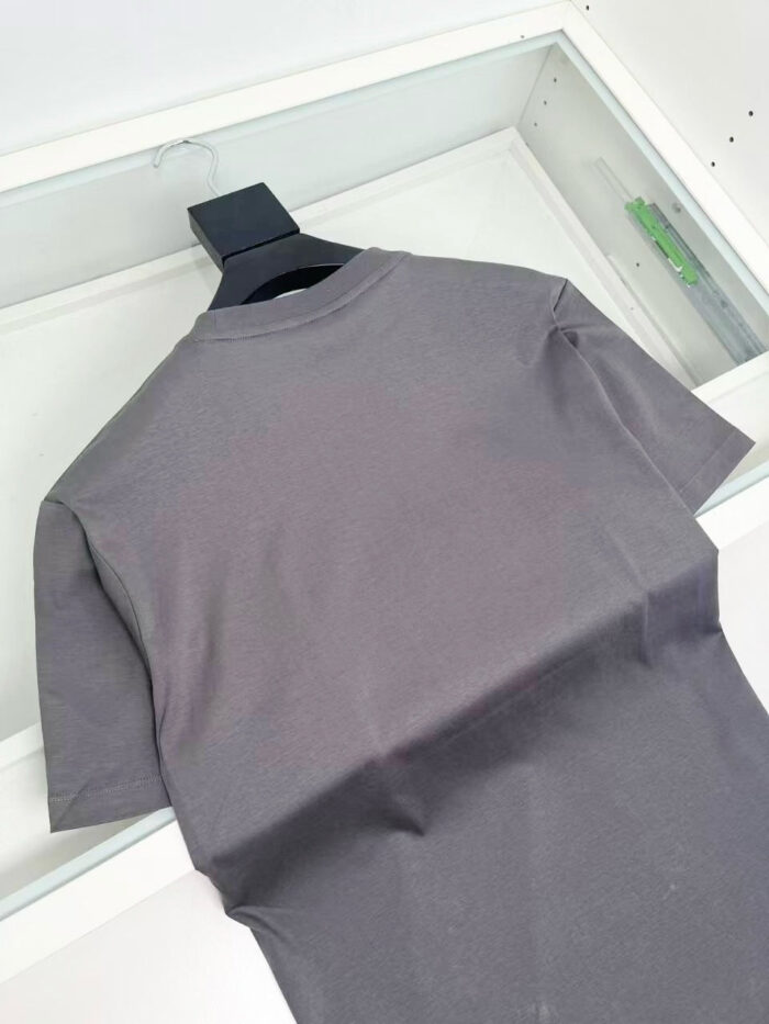 Maglietta grigia semplice vista da dietro su appendiabiti nero, stile casual e versatile.