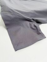 Tessuto grigio leggero con finitura satinata, ideale per abbigliamento casual e versatile.
