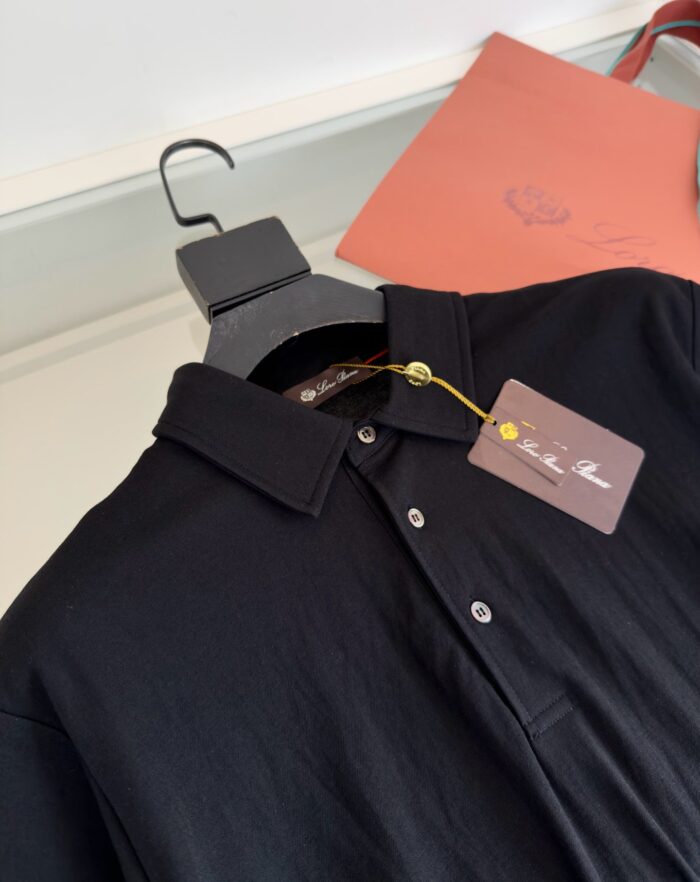 Maglietta polo nera elegante con tag e dettagli di packaging in ambiente retail.