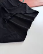 Dettaglio di abbigliamento nero in tessuto, elegante e con cuciture precise.