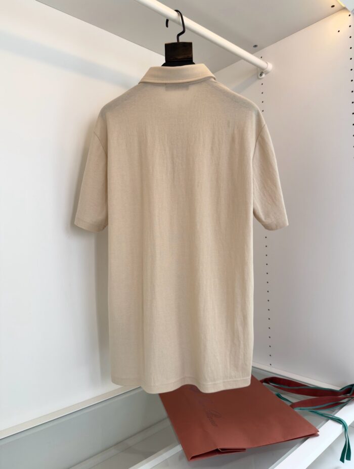 Maglietta polo beige elegante su appendiabiti, stile minimalista e versatile per ogni occasione.