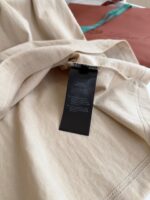 Tessuto beige con etichetta nera, dettagli minimalisti e tocchi di colore in scena elegante.
