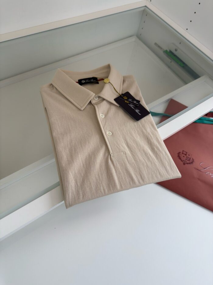 Camicia polo beige su vetro con etichetta e dettaglio di borsa colorata elegante.
