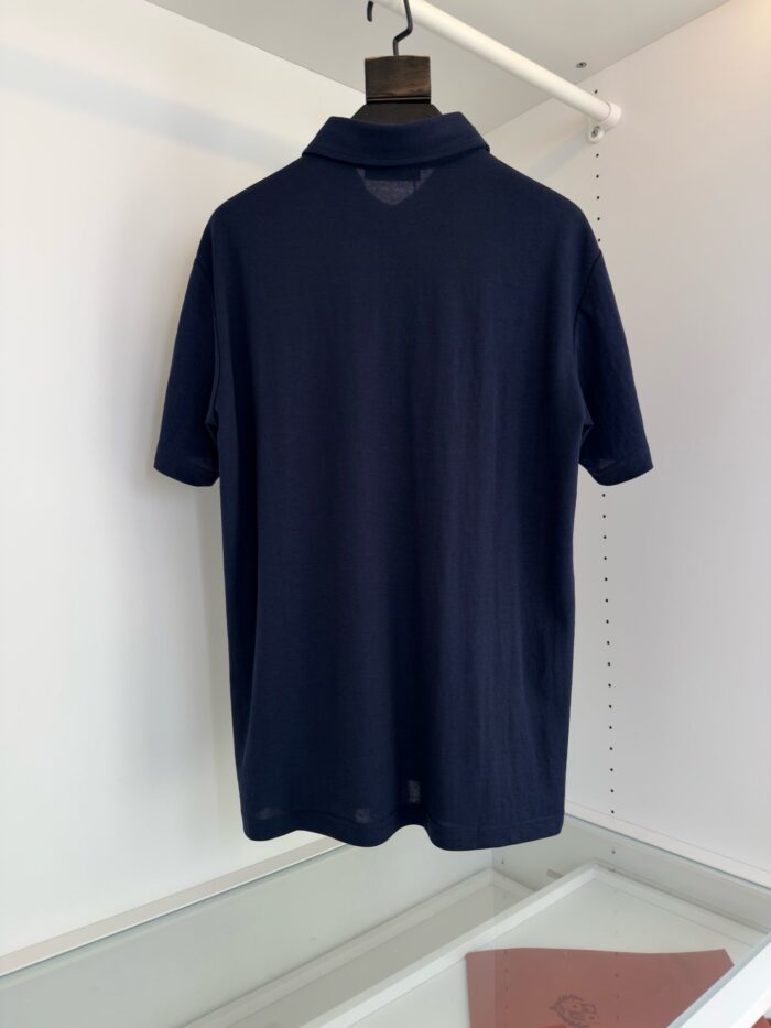 Maglietta polo navy elegante su supporto, dettaglio di alta qualità e stile minimalista