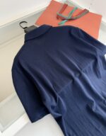 Maglietta polo blu e borsa arancione, stile casual elegante e pratico.