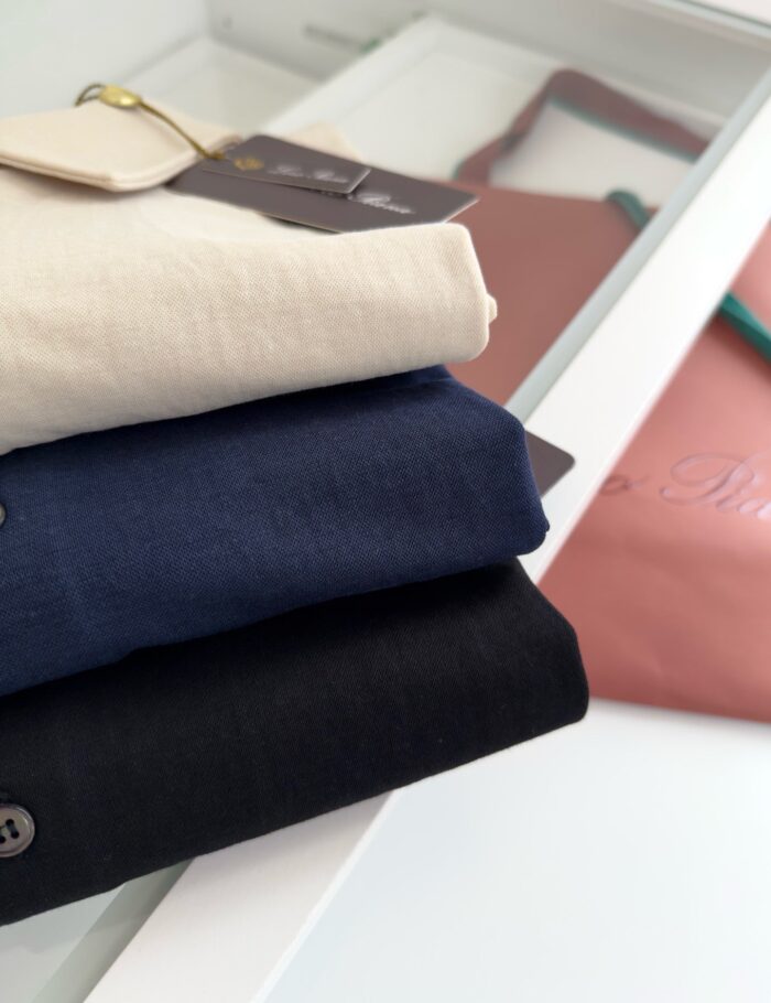 Pile di abbigliamento minimalista con capi colorati neutri, stile semplice ed elegante.
