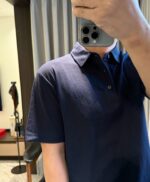 Selfie informale con polo blu in ambiente moderno e luminoso.