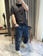 Persona in abbigliamento casual elegante con jeans, polo e sneakers in ambiente moderno.