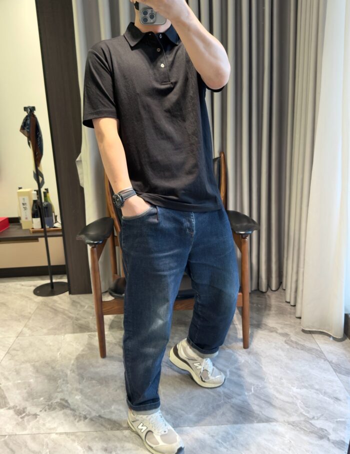 Persona in abbigliamento casual elegante con jeans, polo e sneakers in ambiente moderno.