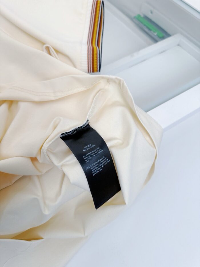 Maglietta beige con etichetta nera minimalista, stile moderno e elegante, su sfondo neutro.